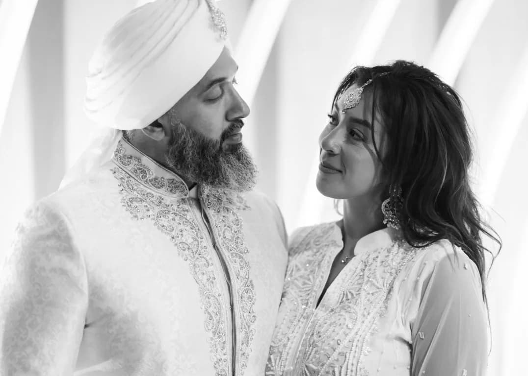 A bride and groom in white and silver looking at each other
